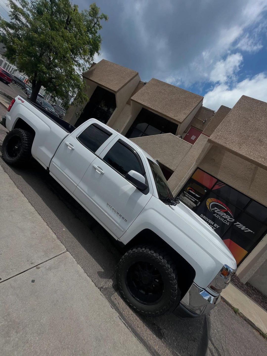 white tinted truck infront of turbo tint arvada with clouds in the back