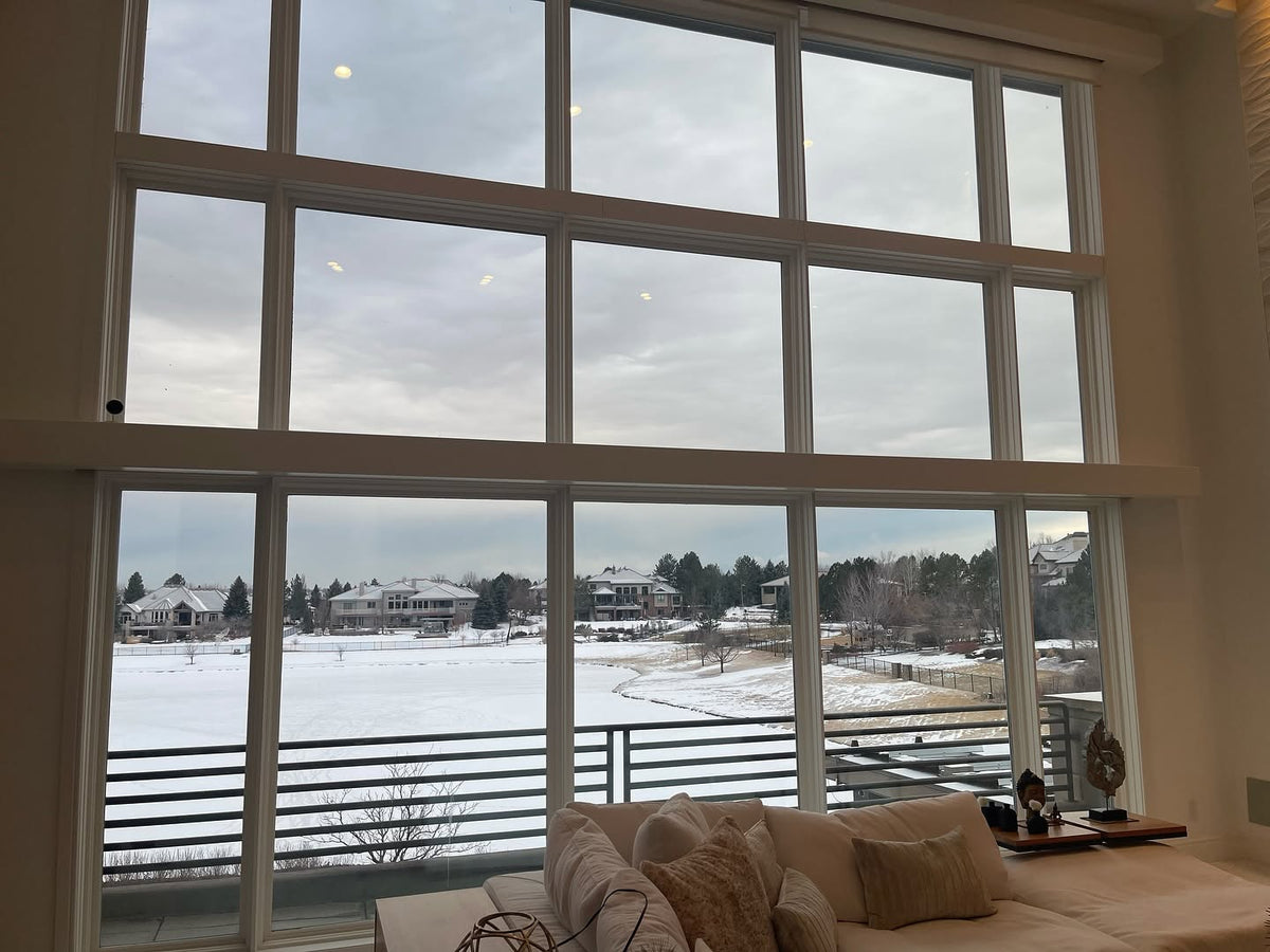 Living room with large windows showing a snowy landscape before window tint installation 