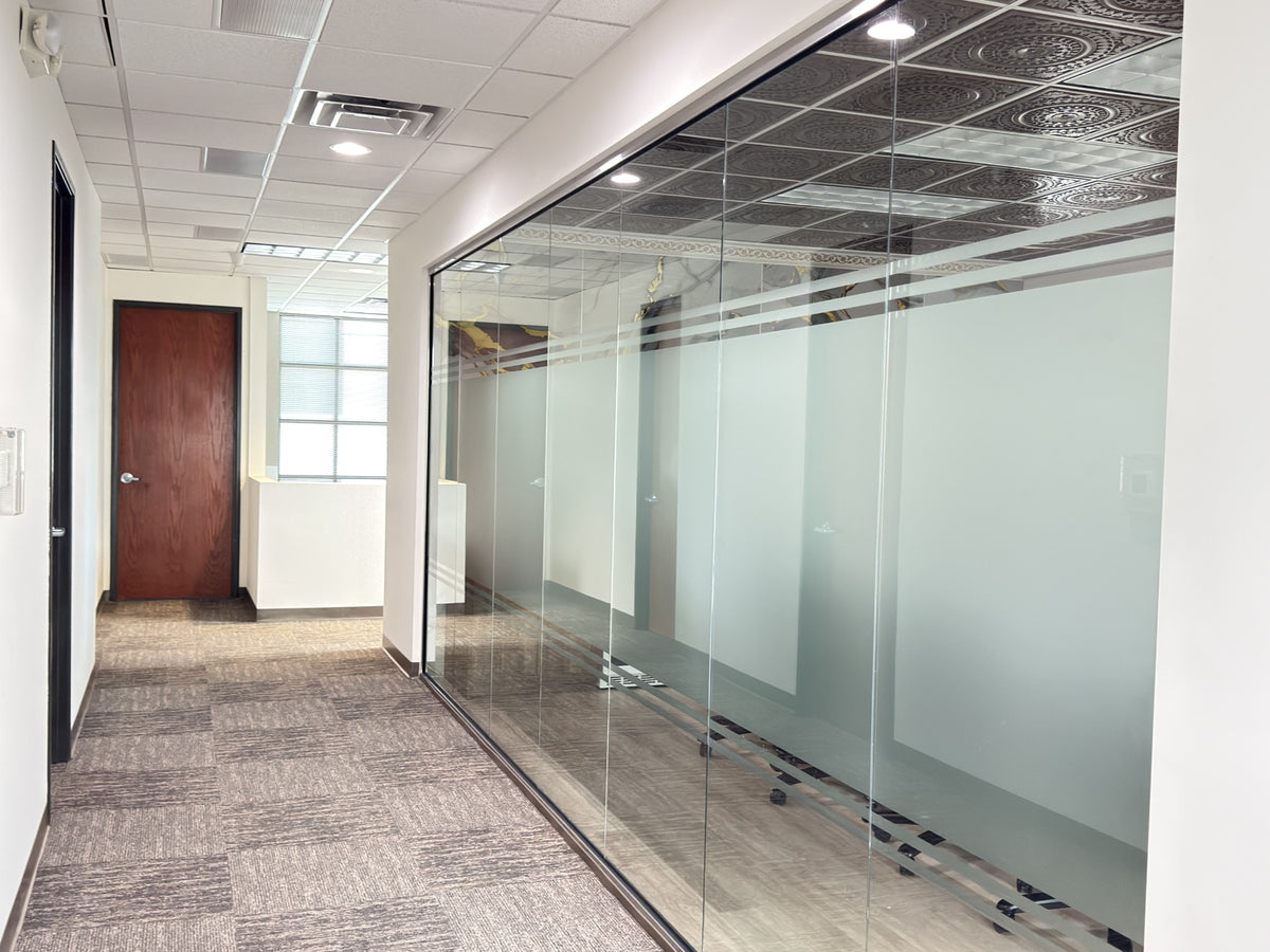 Modern office conference room with glass walls and a meeting table with window film for decor and privacy